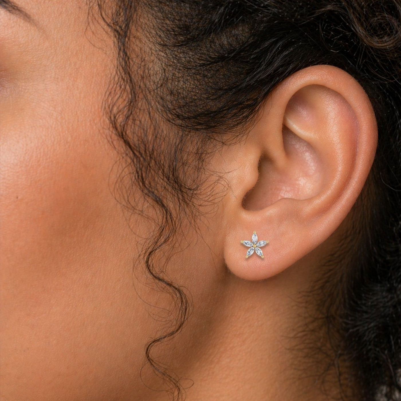 A close-up of a person's ear wearing a small silver star-shaped stud earring with clear stones.