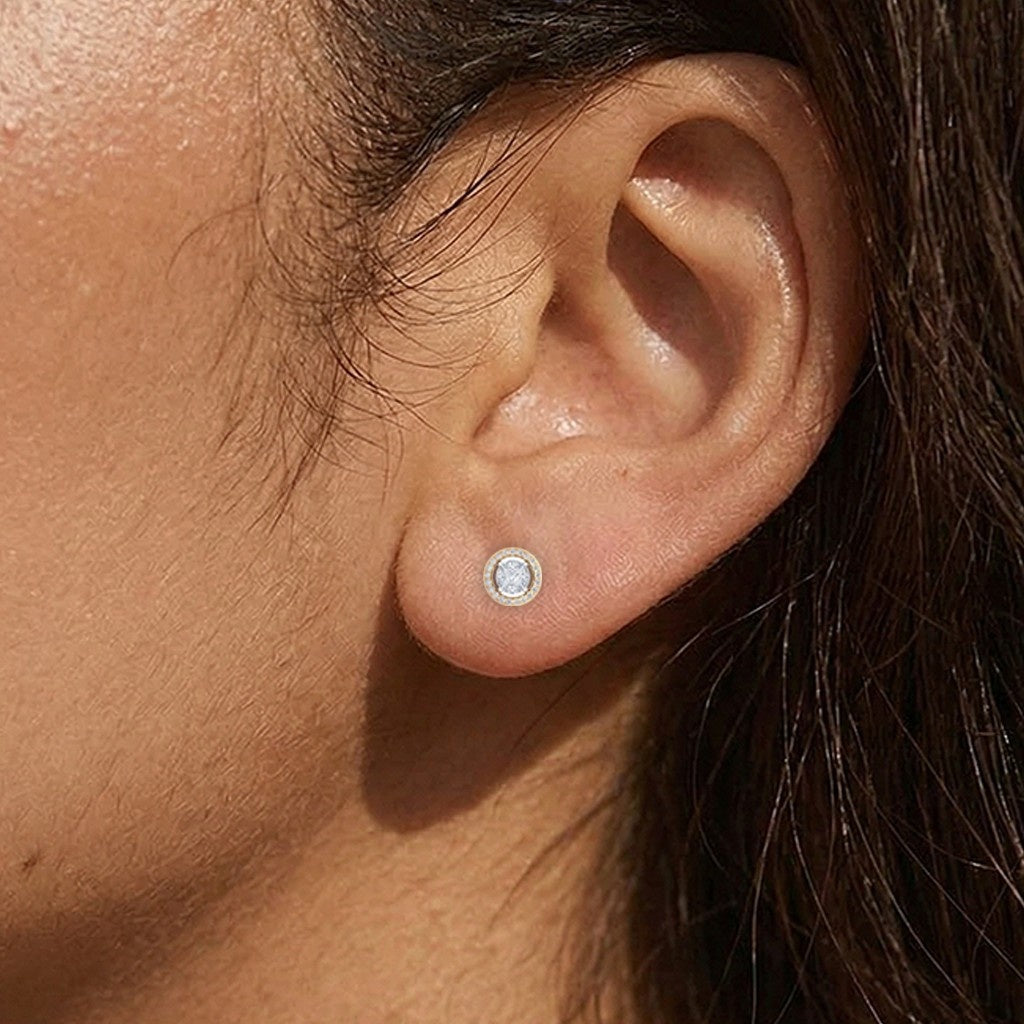 A close-up of a person's ear wearing a small round stud earring.