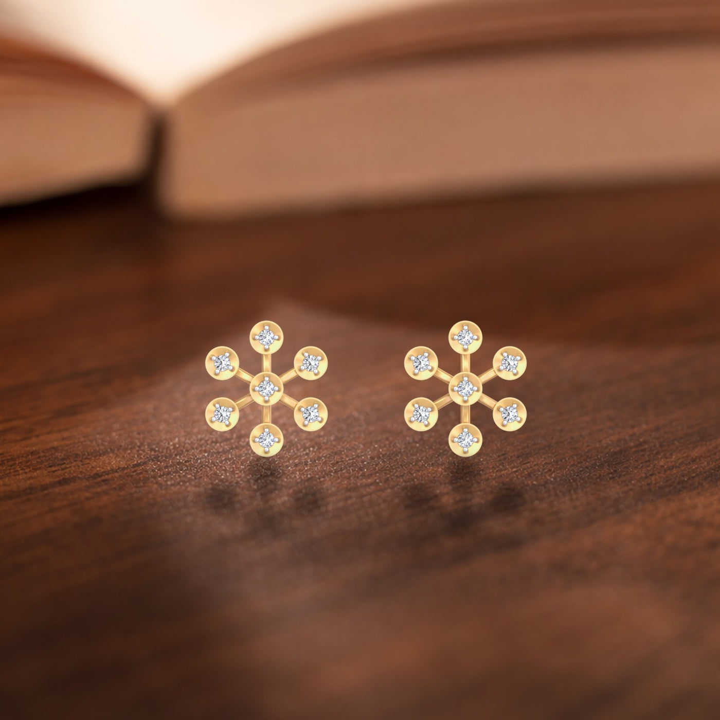 A pair of gold and diamond stud earrings with a floral design set, resting on a dark wooden surface.