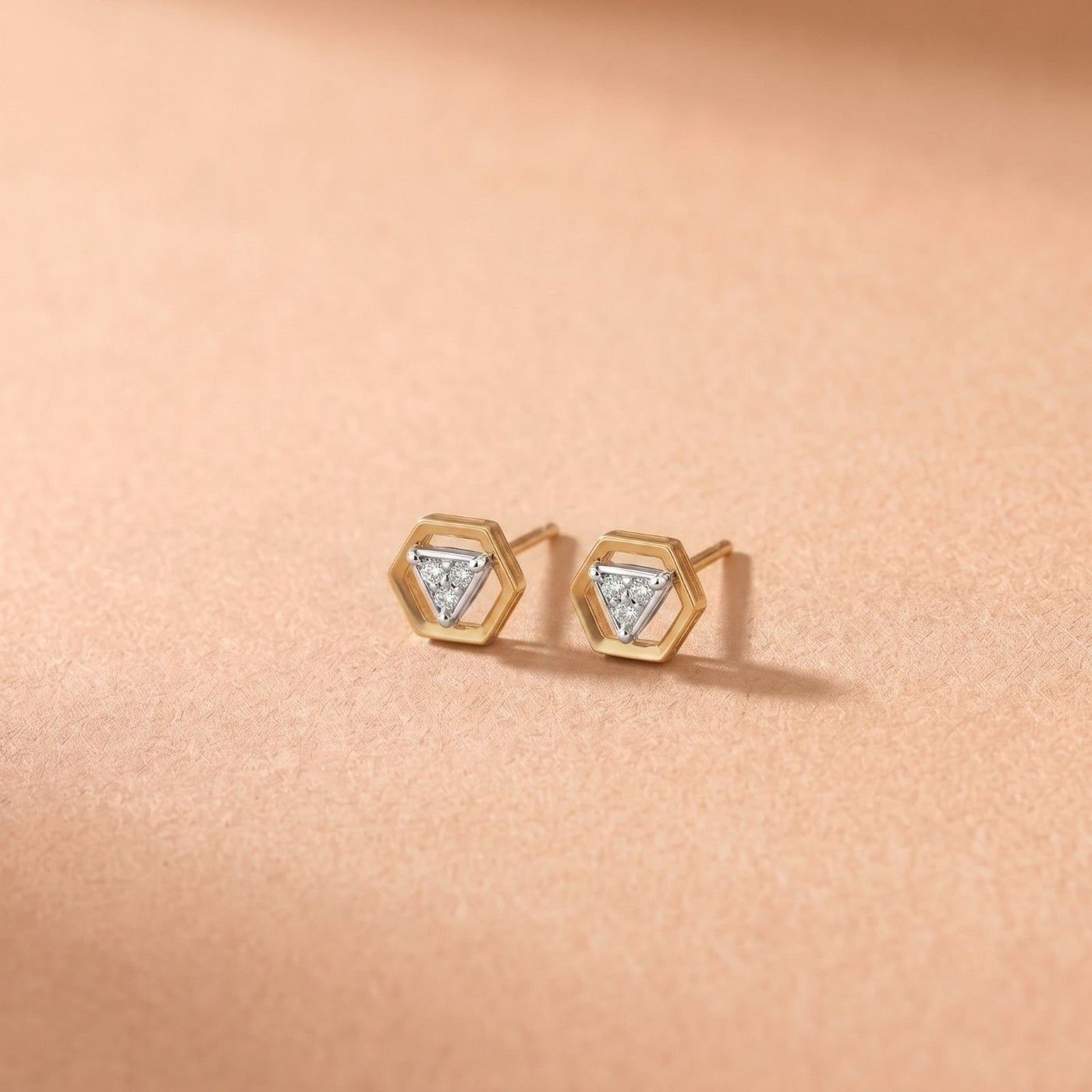 Gold and diamond stud earring on a pink background.