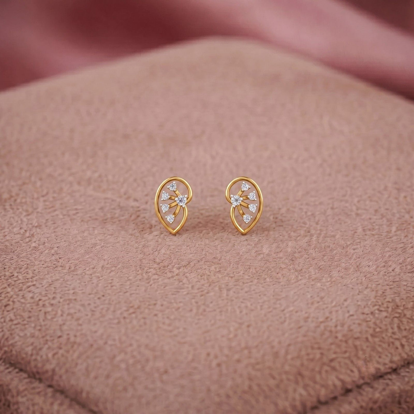 Gold and diamond stud earring on a brown fabric background.
