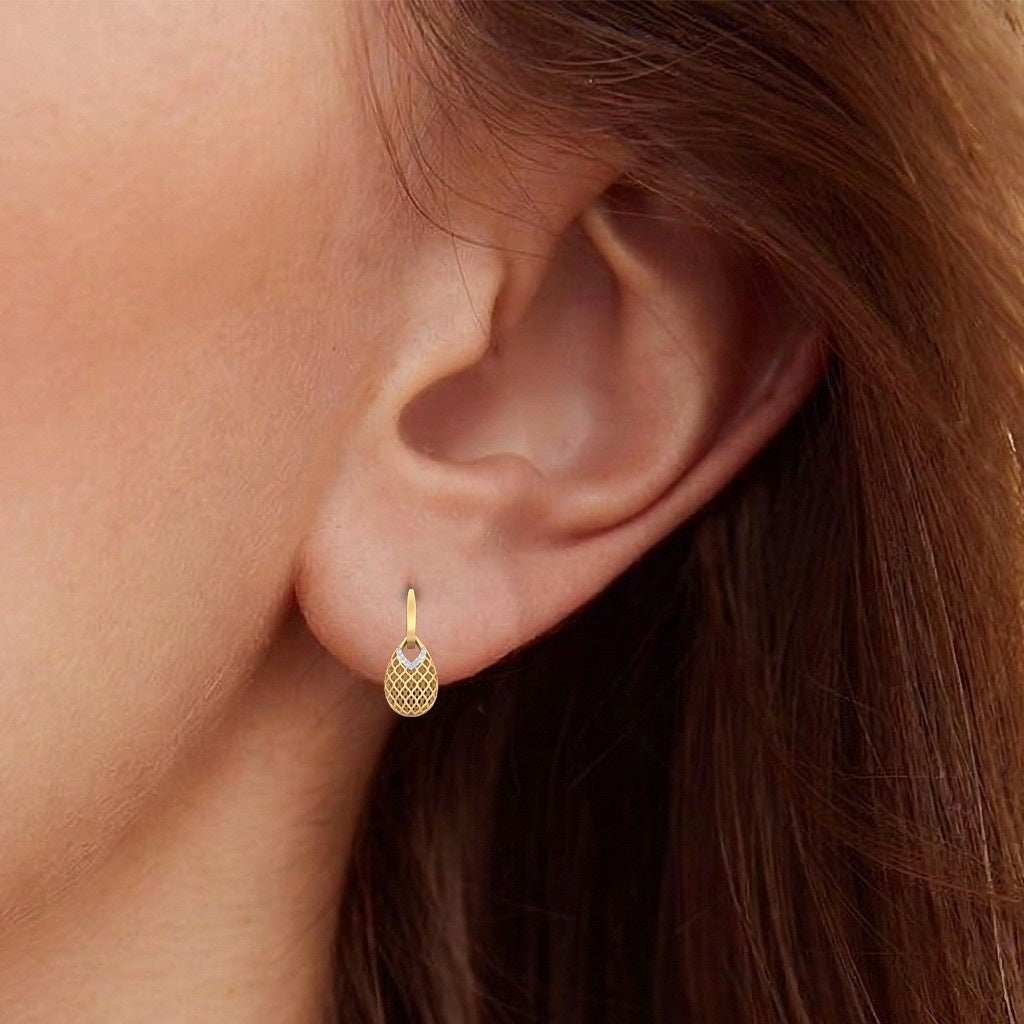 A close-up of a model's ear wearing a gold hoop earring.