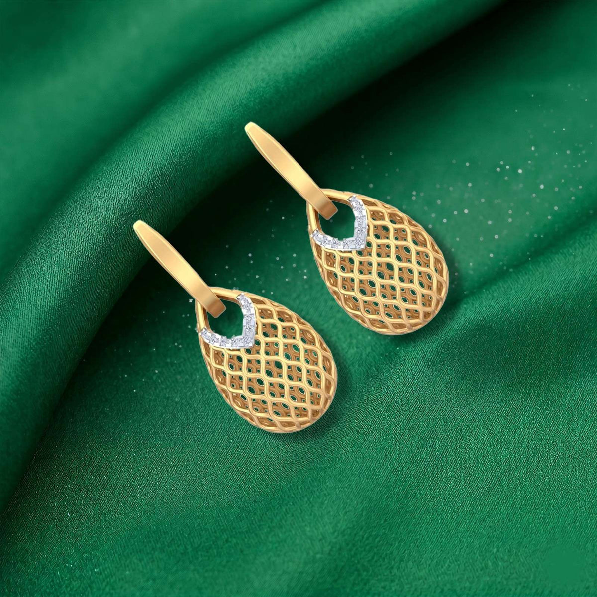 Gold hoop earrings with diamond accents, displayed on a draped green fabric background.
