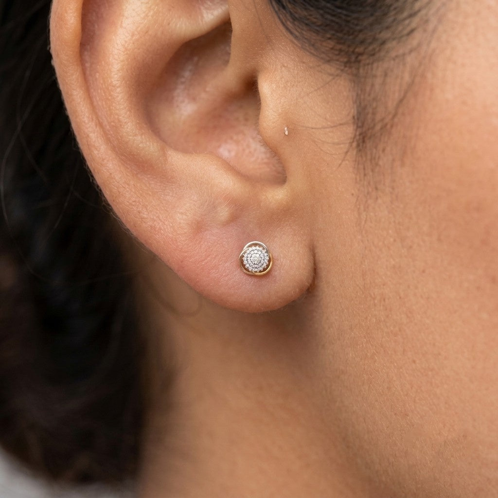 A close-up of a person's ear wearing a round stud earring and a center cluster.