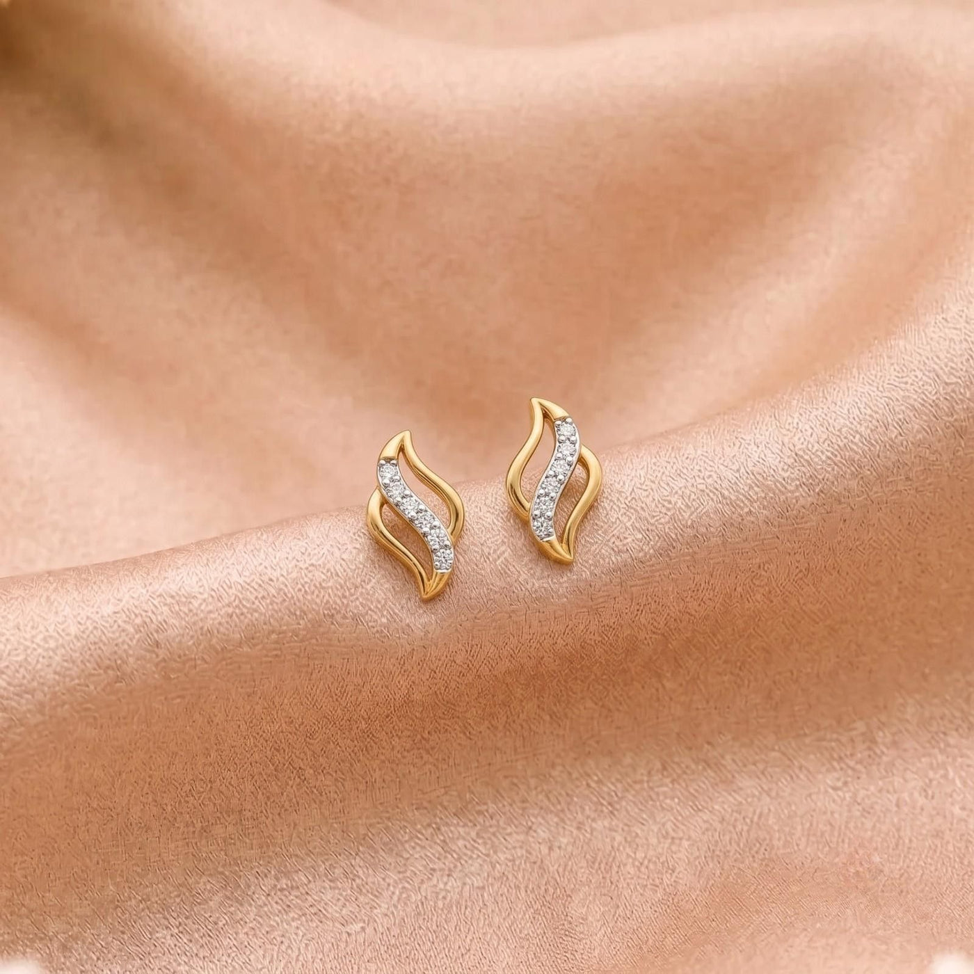 Gold  and diamond swirl curve stud earring on a beige fabric