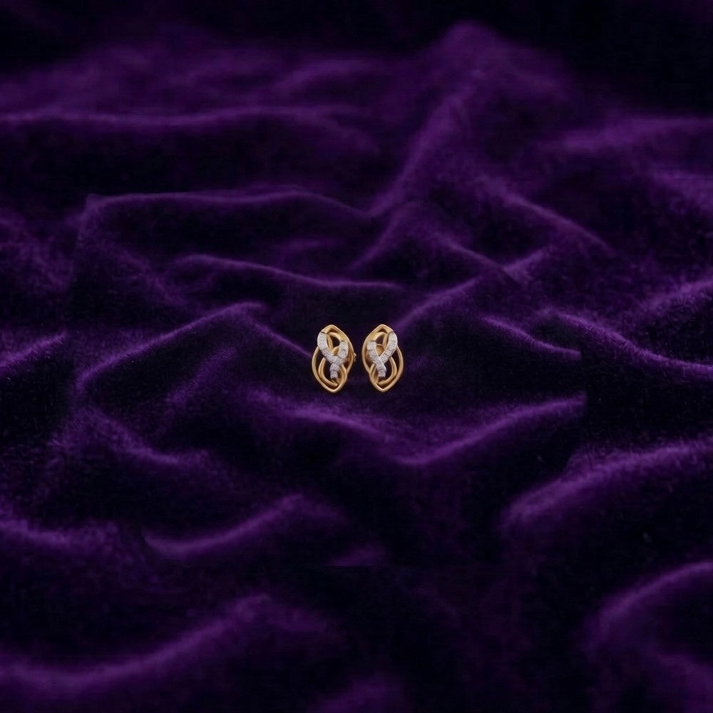 Gold and diamond stud earrings on a purple textured fabric background.