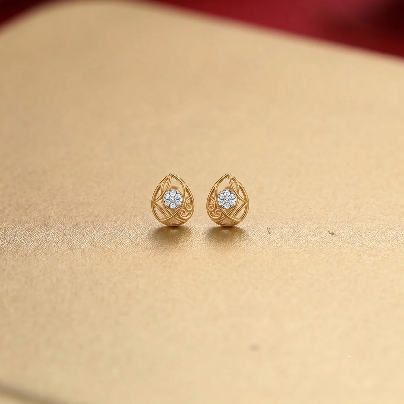 Gold and diamond teardrop-shaped earrings on a golden background