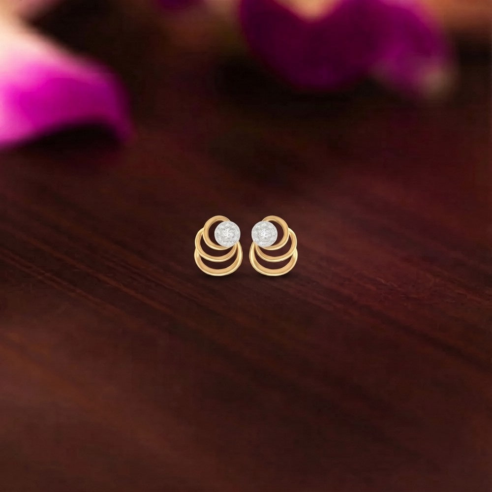 Gold and diamond stud earrings on a wooden surface