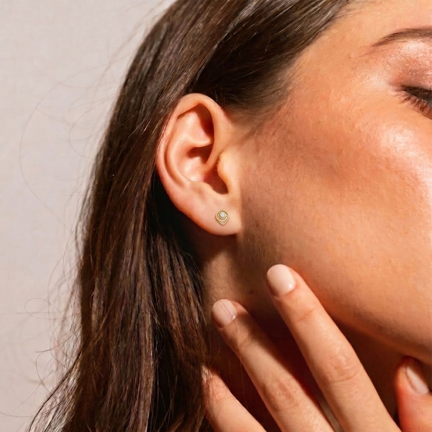 A close-up of a woman's ear wearing a gold hoop earring.