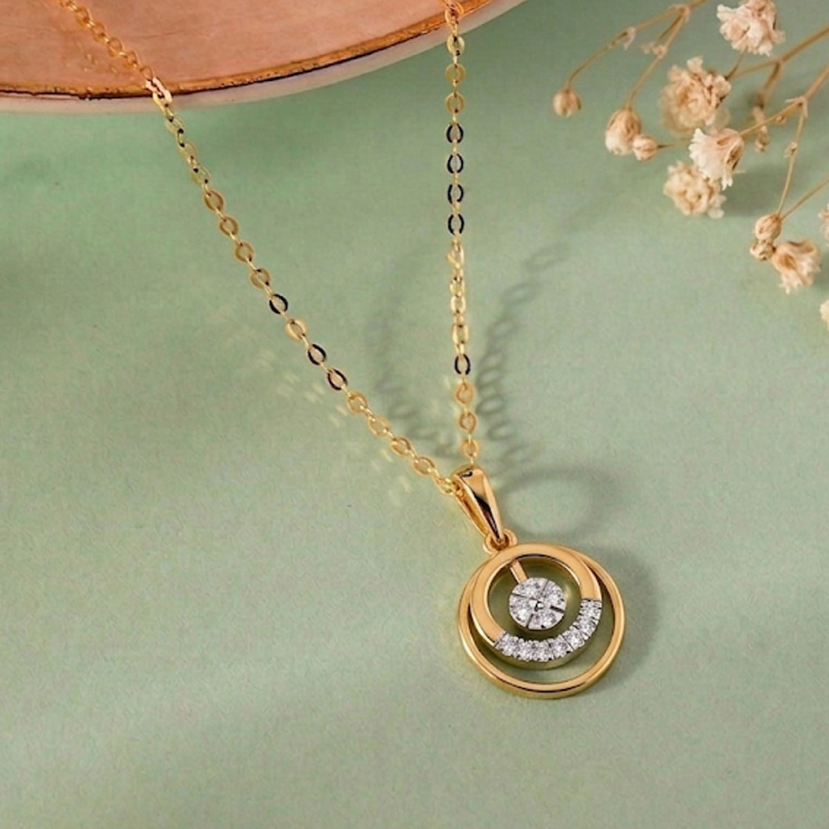 Gold and diamond with a circular pendant on a green surface