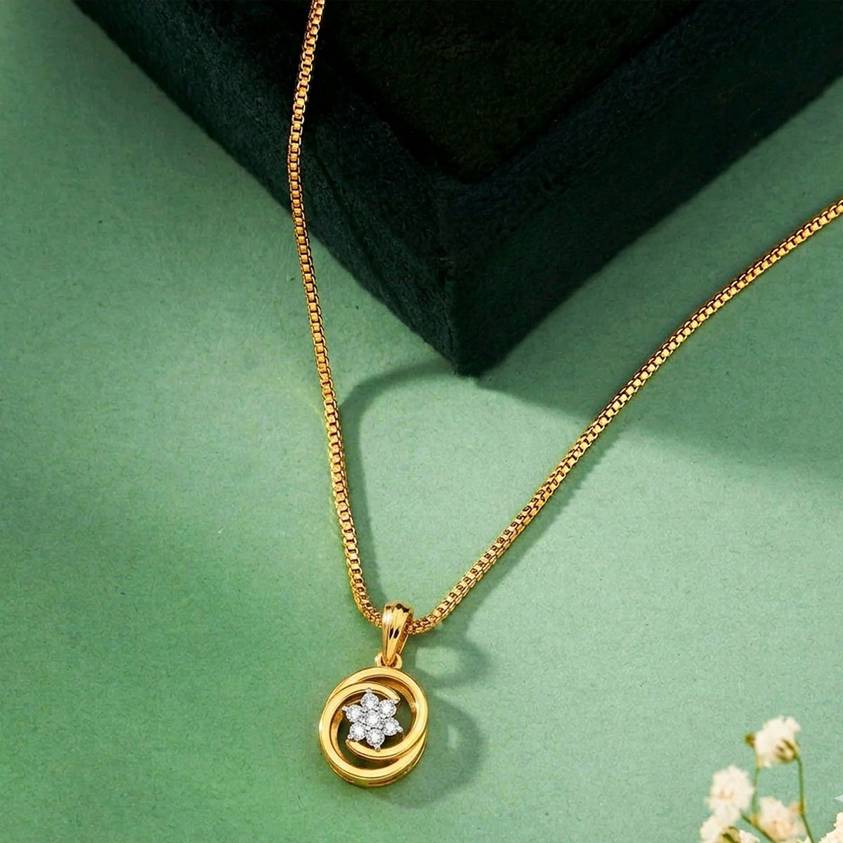 Gold and diamond pendant with a green background