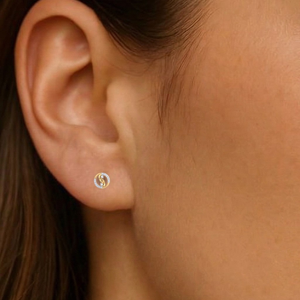 Close-up shot of a circular two-tone gold and diamond stud earrings.