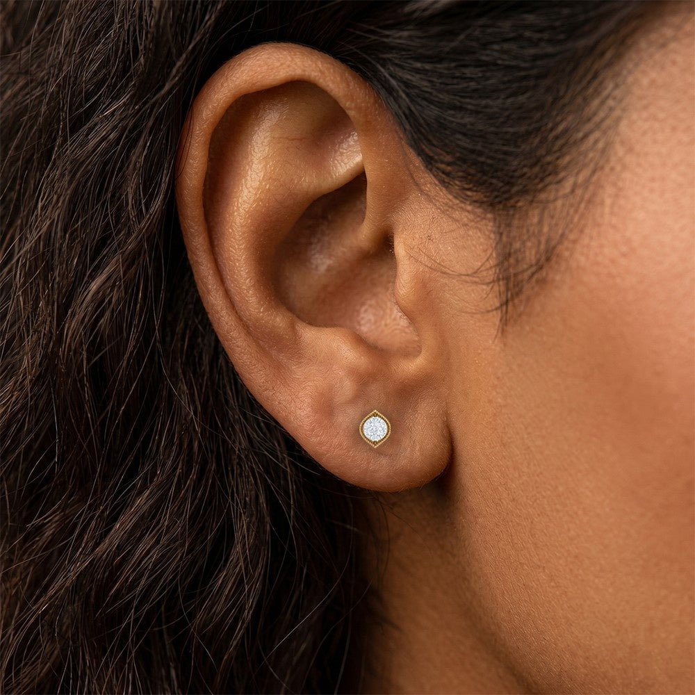 A close-up of a person's ear wearing a gold and earring round stud. earring.