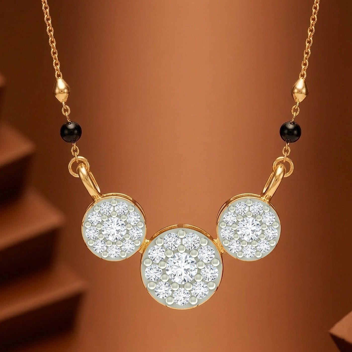 Gold magalsutra with three circular pavé crystal pendants and small black beads on a warm brown gradient background.
