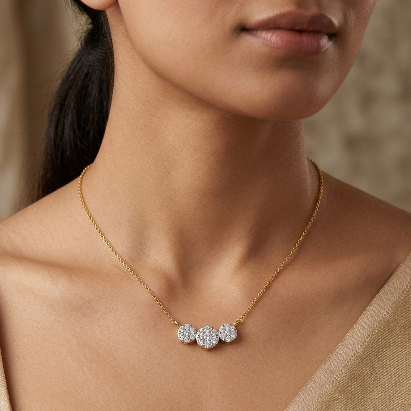 A close-up of a person wearing a fine gold chain mangalsutra with a horizontal pendant made of three connected, diamond-paved circles