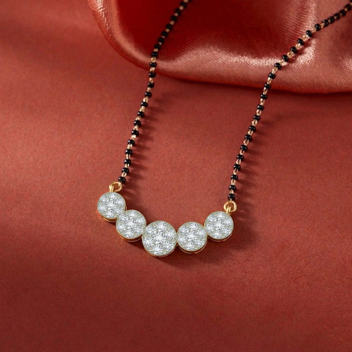 gold and diamond round mangalsutra on red background
