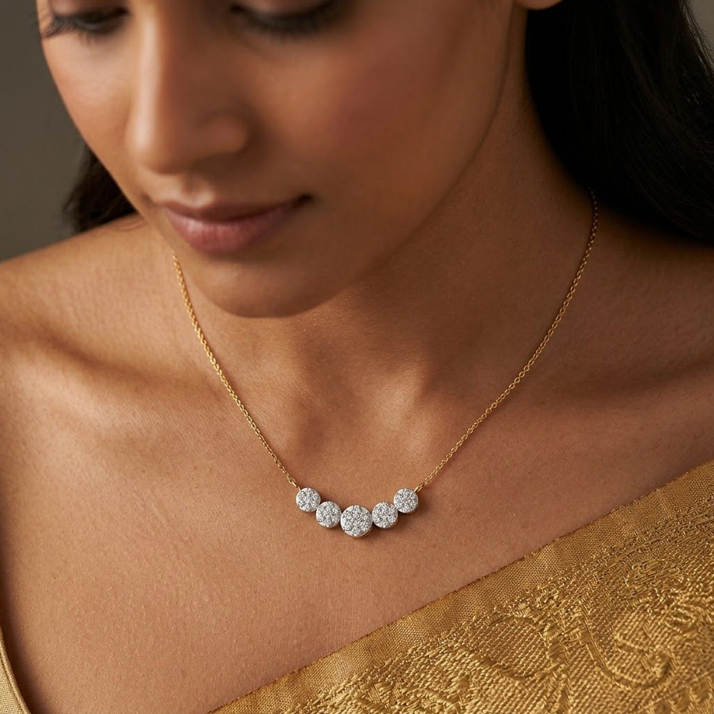 A close-up lifestyle shot of a woman wearing a delicate gold mangalsutra with five sparkling round-cut clear stones set in a curved row on a gold chain.