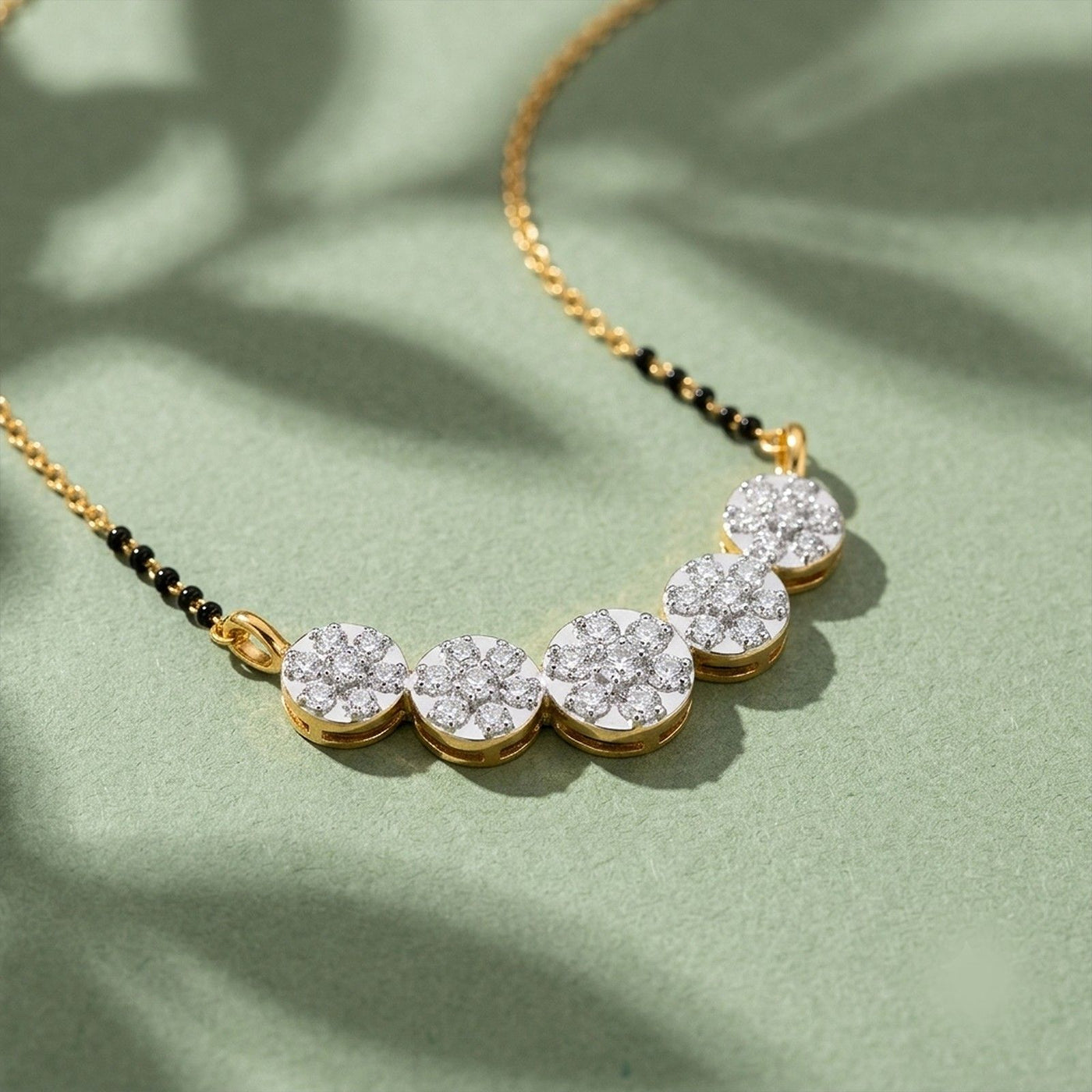 A close-up of a person wearing a fine gold chain mangalsutra with a horizontal pendant made of three connected, diamond-paved circles