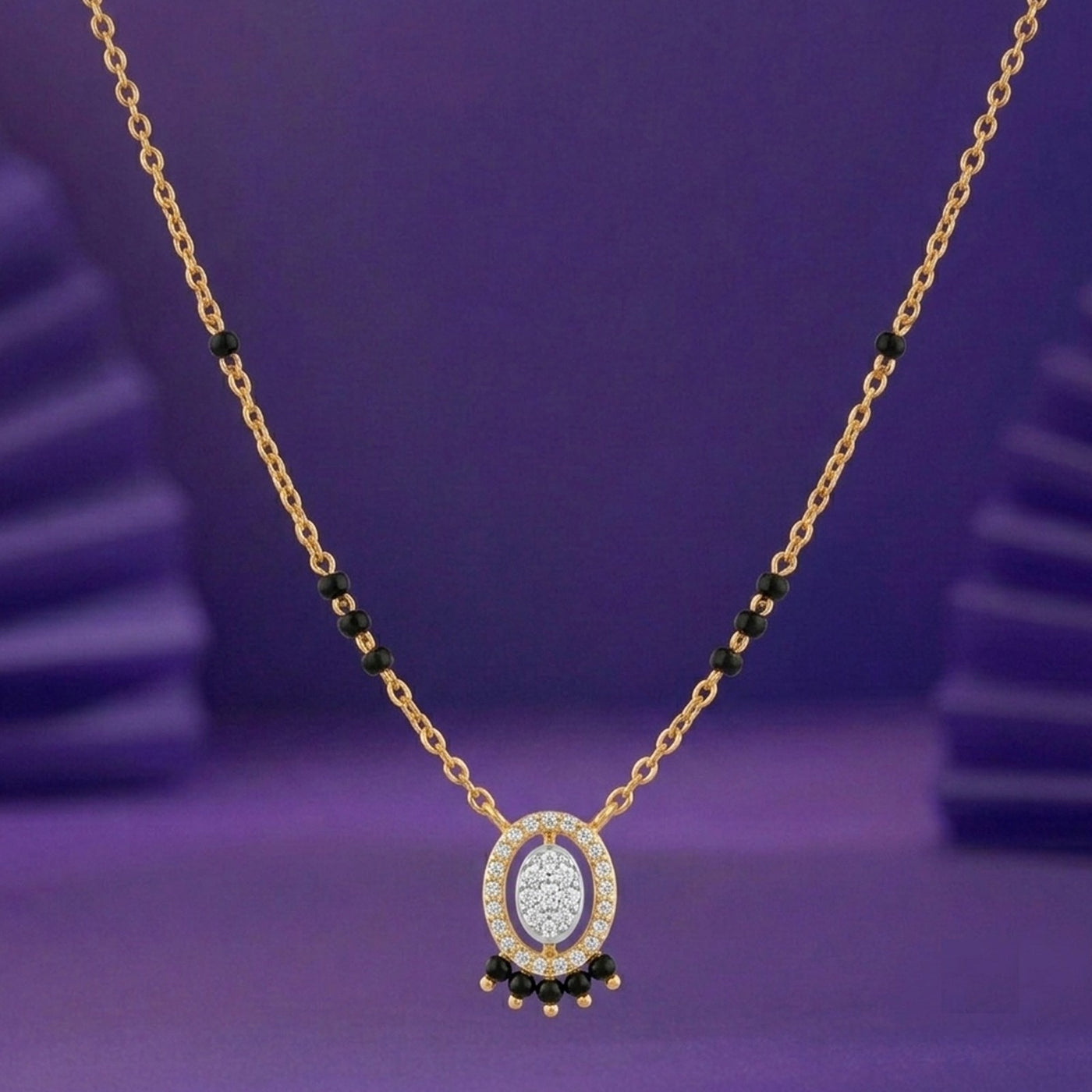 A gold mangalsutra with a central featuring a sparkling silver-toned center, surrounded by small clear stones and accented with black beads, set against a purple background.