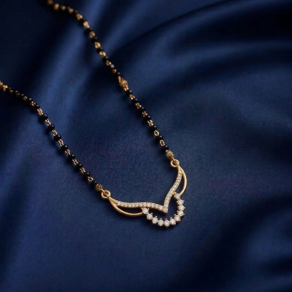A gold and diamond mangalsutra with a curved diamond adorned with small clear stones, displayed on a dark navy blue satin fabric background.