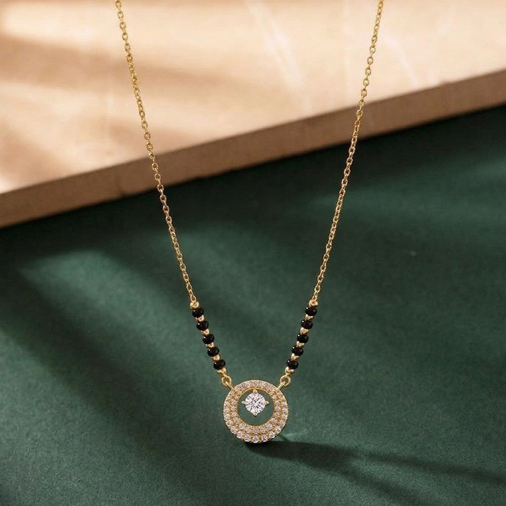 Gold and diamond mangalsutra with a circular diamond on a green surface