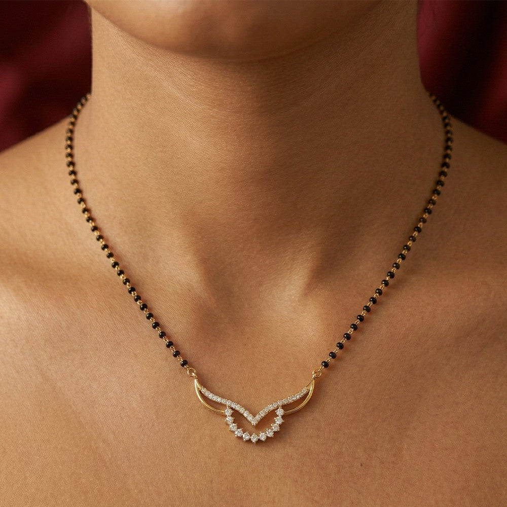 gold and diamond mangalsutra on a person's neck against a neutral background