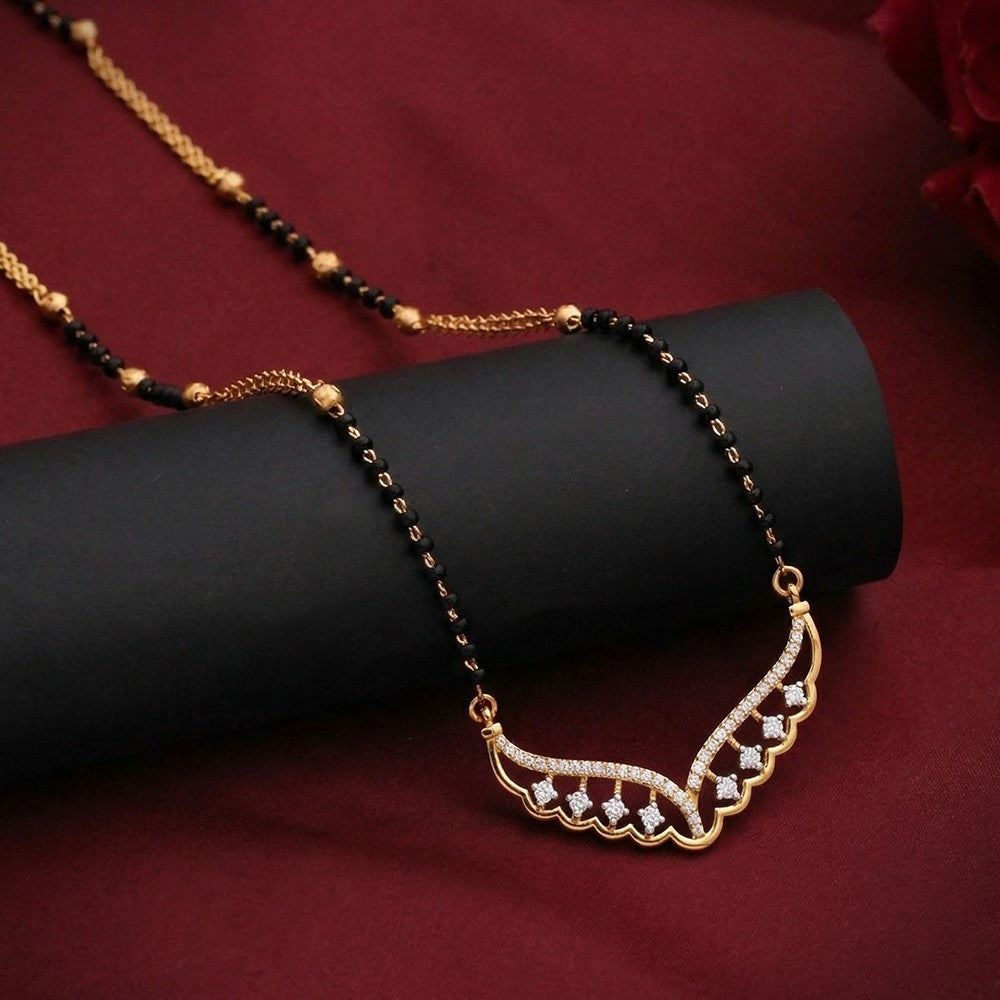 gold and diamond mangalsutra with a scalloped crescent moon pendant set with small clear stones, displayed on a black cylindrical stand against a dark red background.