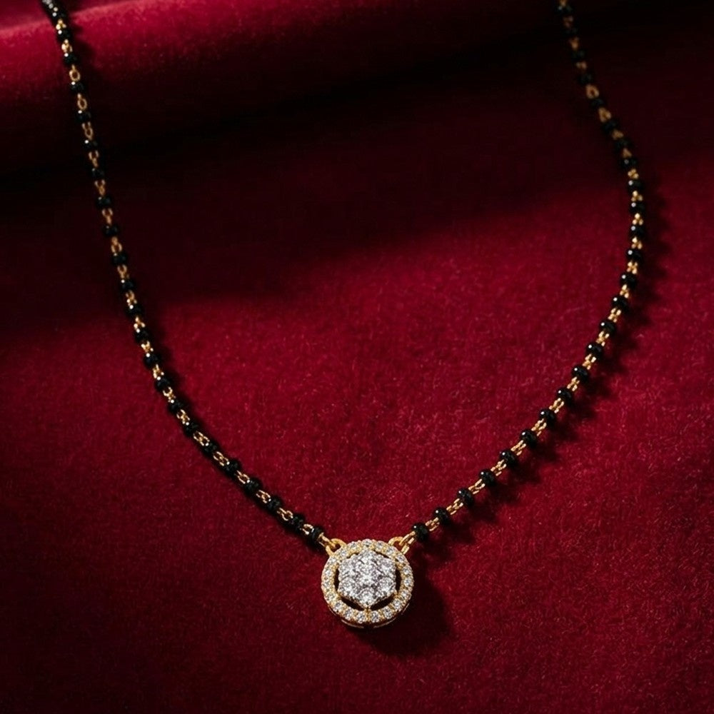 A yellow gold and diamond mangalsurta with a gold-toned circular paved with clear stones, displayed on a deep red velvet background.