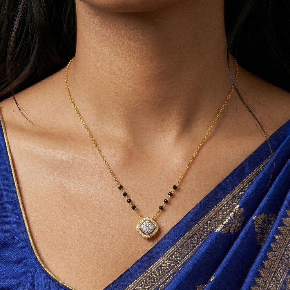 gold and diamond mangalsutra on a person wearing a blue saree.
