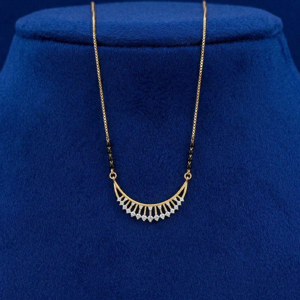 A yellow gold and diamond mangalsutra with small clear stones along the bottom curve, displayed on a dark blue velvet jewelry bust.