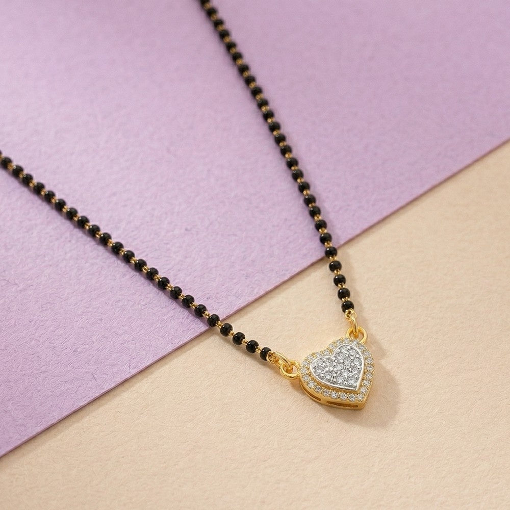 Black beaded mangalsutra with a gold and diamond on a two-tone pink and beige background