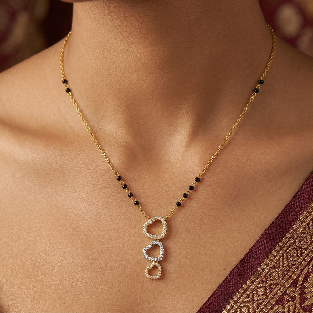 gold and diamond mangalsutra with a heart-shaped mangalsutra on a person wearing a maroon saree.