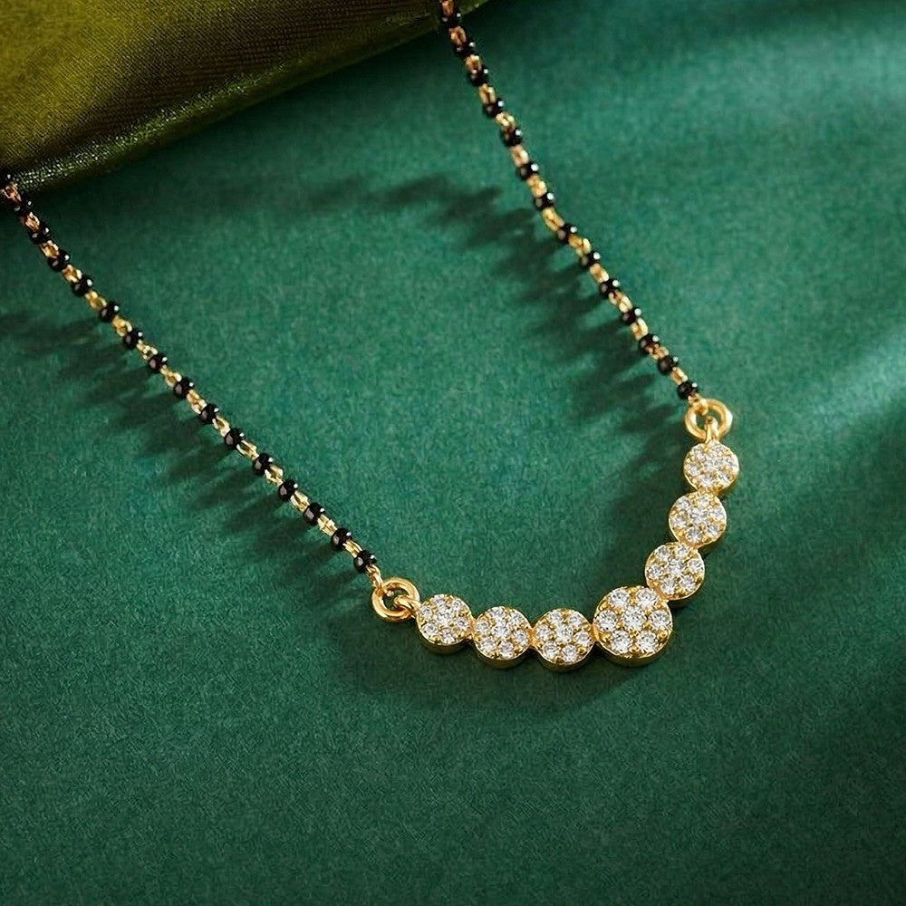 Gold and diamond mangalsutra with black beads on a green fabric background