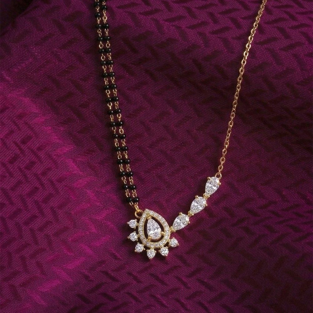 Gold mangalsutra with a diamond pendant on a purple textured fabric background