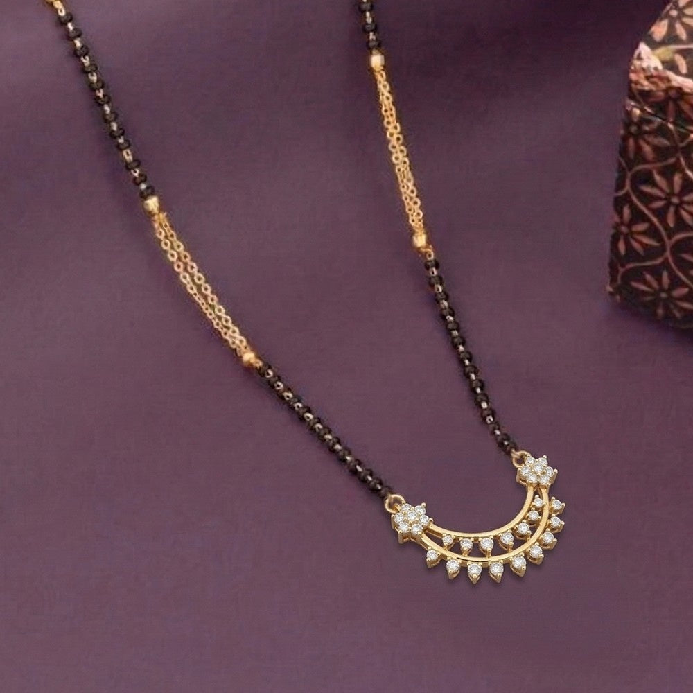 A gold and diamond black beaded mangalsutra with a crescent moon pendant adorned with small clear stones, displayed on a dark purple background.