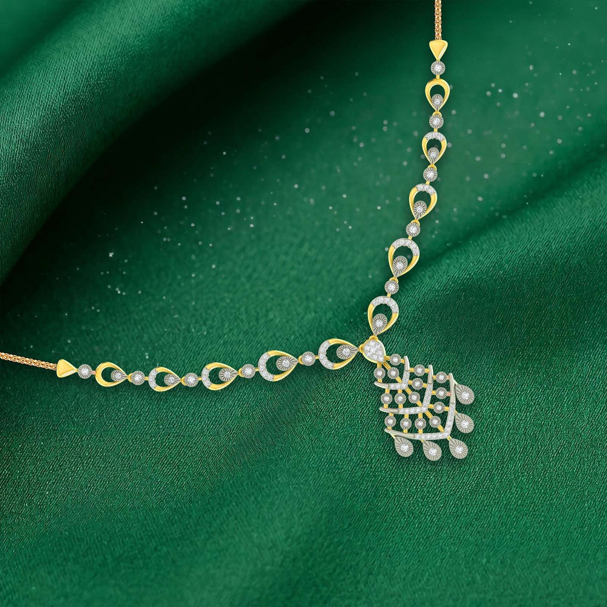 Gold and diamond necklace with teardrop shaped, displayed on a solid green fabric background.
