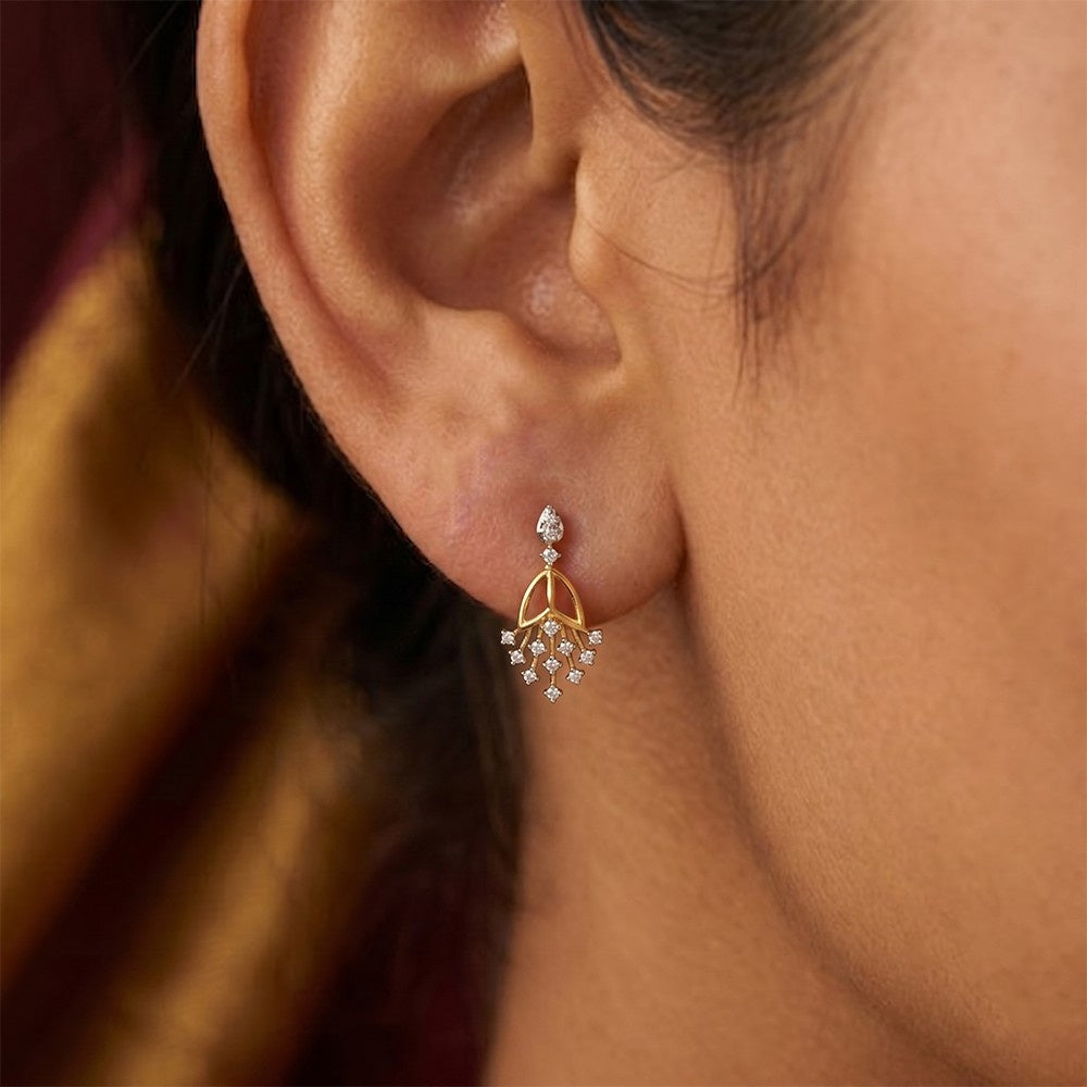 A close-up of a person's ear wearing a gold and diamond earrings.
