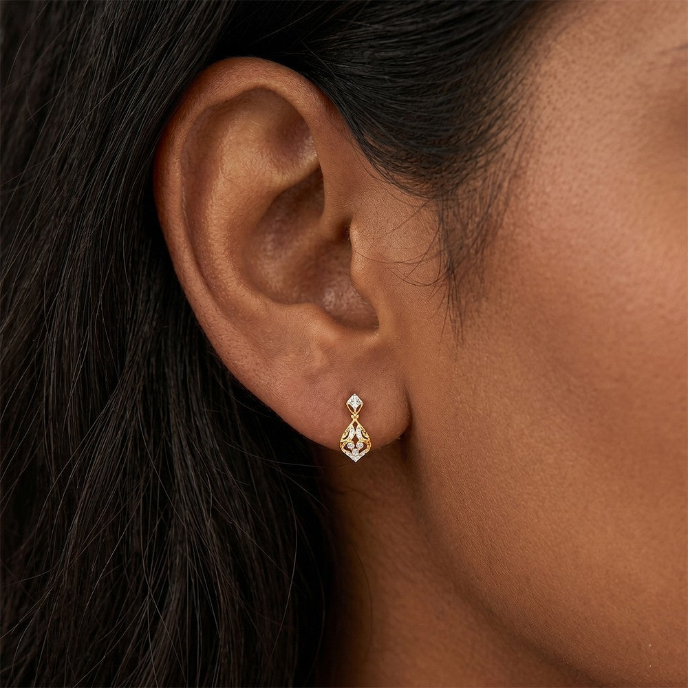 A close-up of a model's ear wearing a gold teardrop-shaped drop earring with diamond.