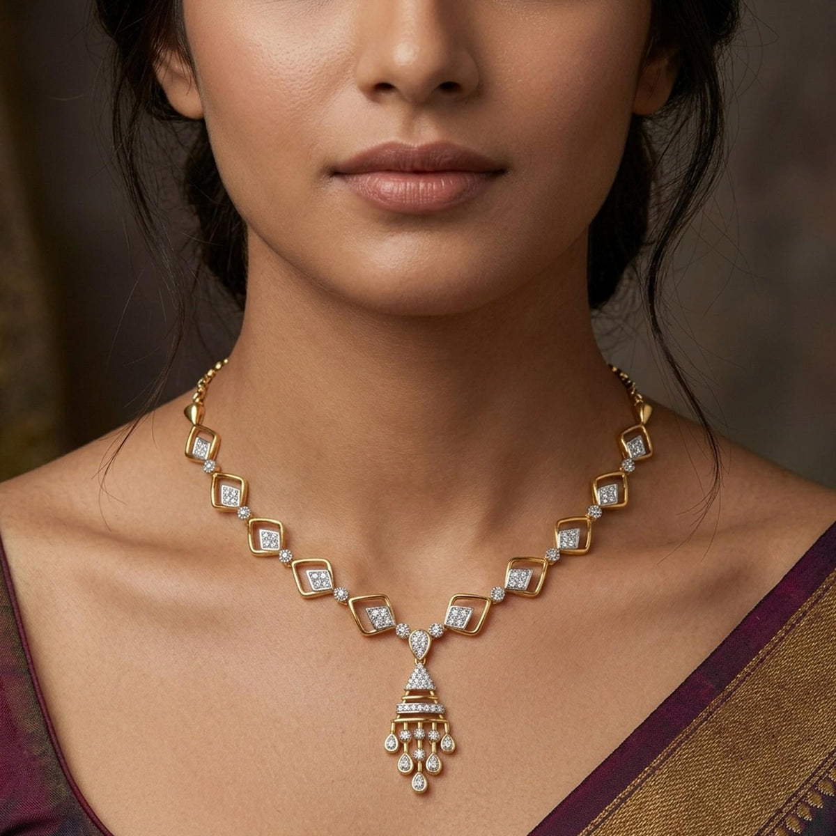 Gold and diamond necklace worn by a model, featuring a geometric diamond-shaped.