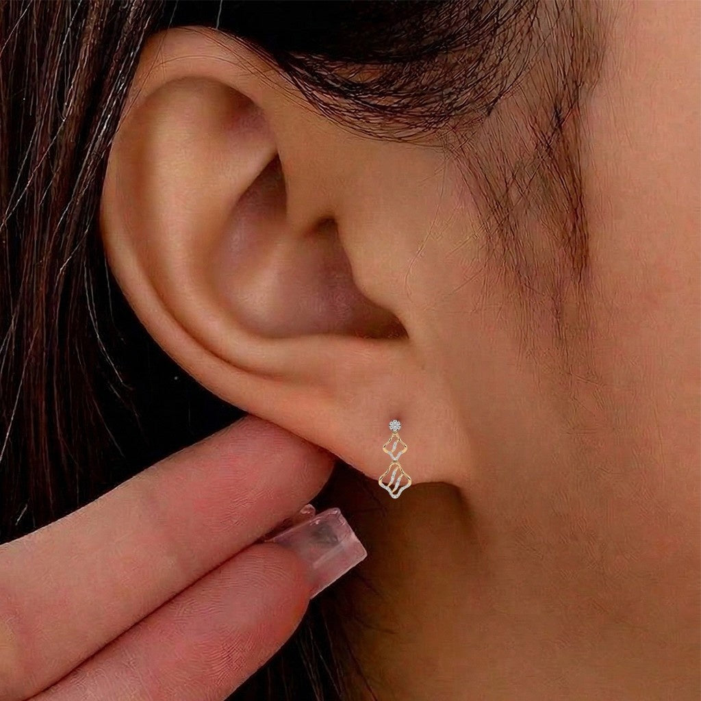 A close-up of a person's ear wearing a wavy dangling design earring.