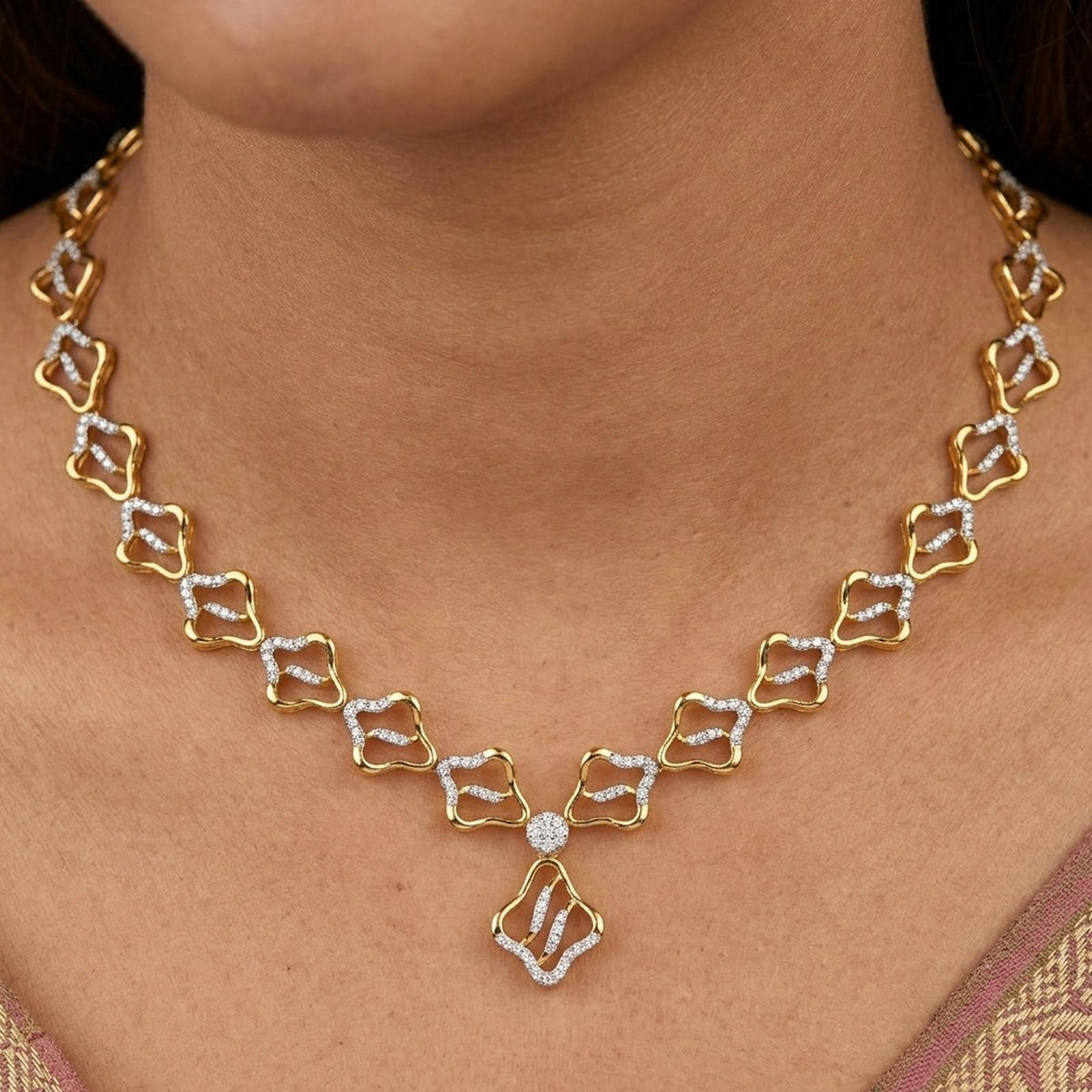 A close-up of a gold and diamond necklace worn on a model's neck. The necklace features a repeating geometric.