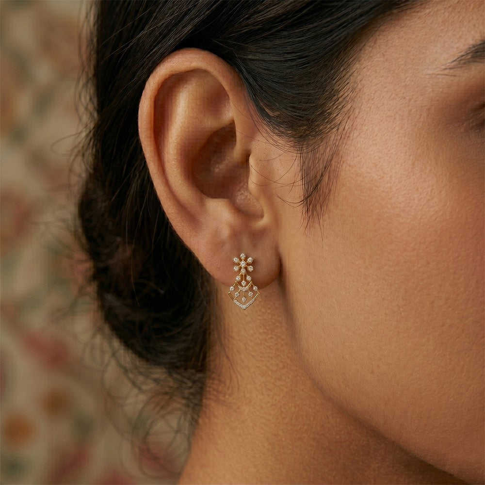 A close-up of a woman's ear wearing a gold earrings with floral-design.