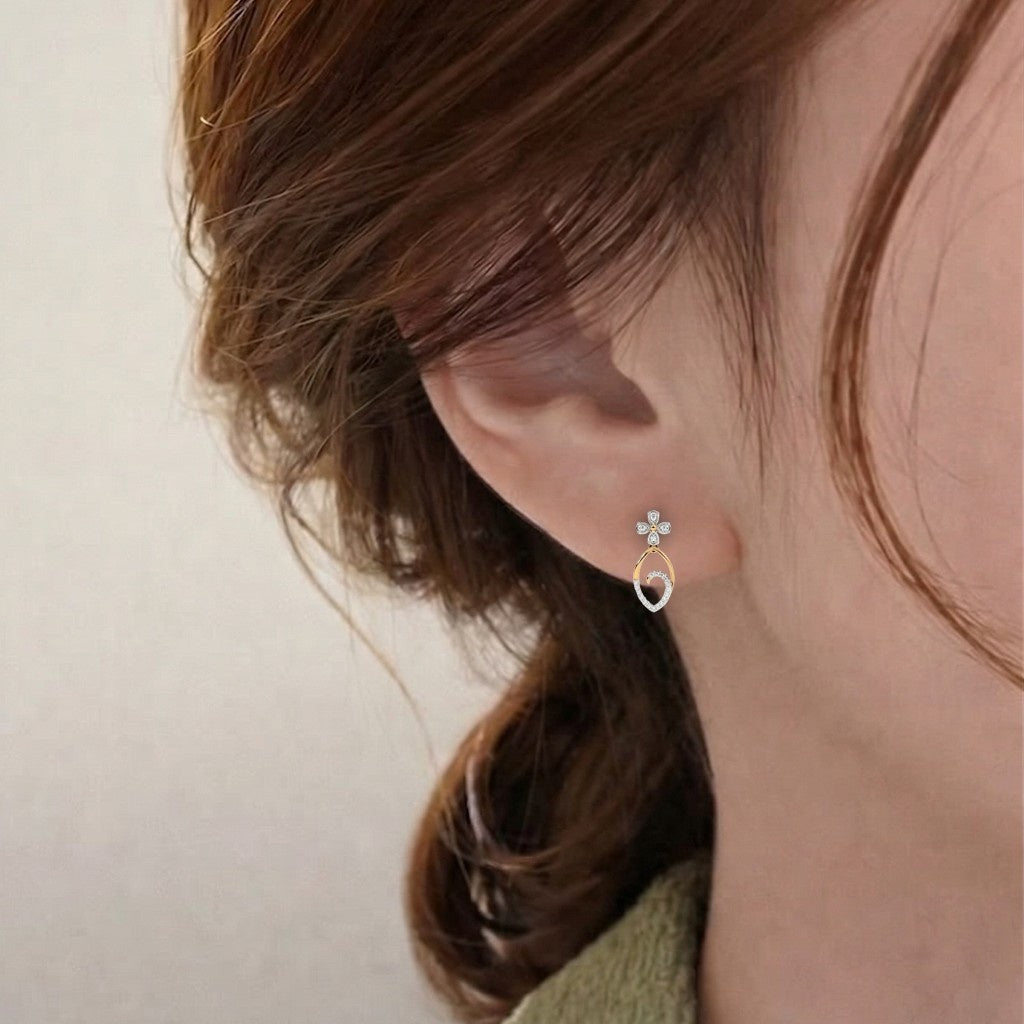 A close-up of a person's ear wearing a delicate gold and diamond earring.