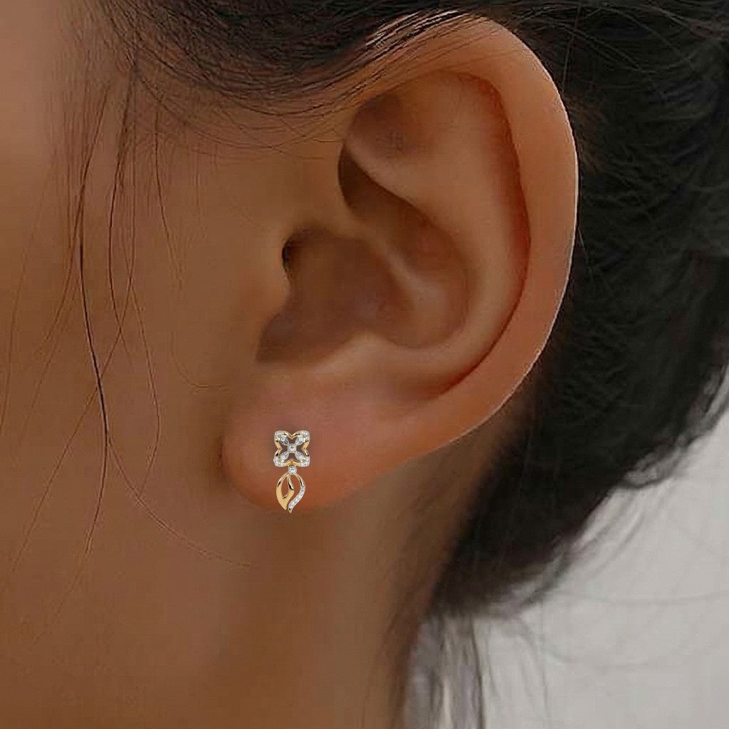 A close-up of a person's ear wearing a gold earring with flower motif and a dangling gold leaf accent.