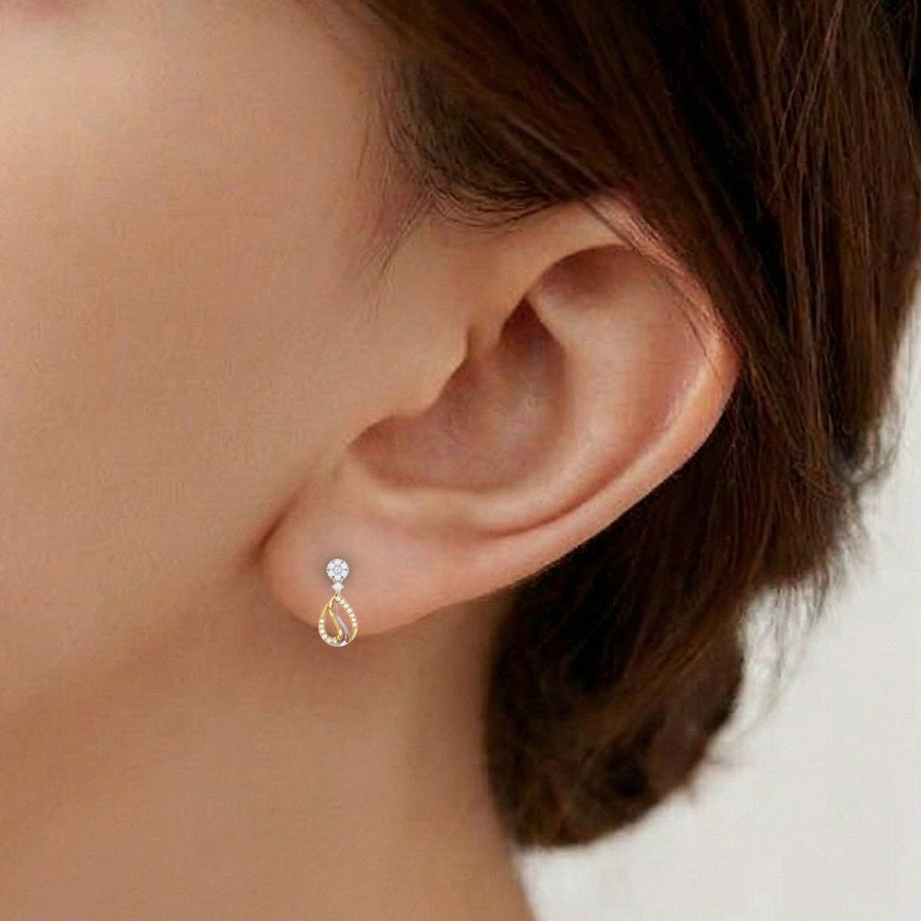 A close-up of a person's ear wearing a gold teardrop-shaped earring.