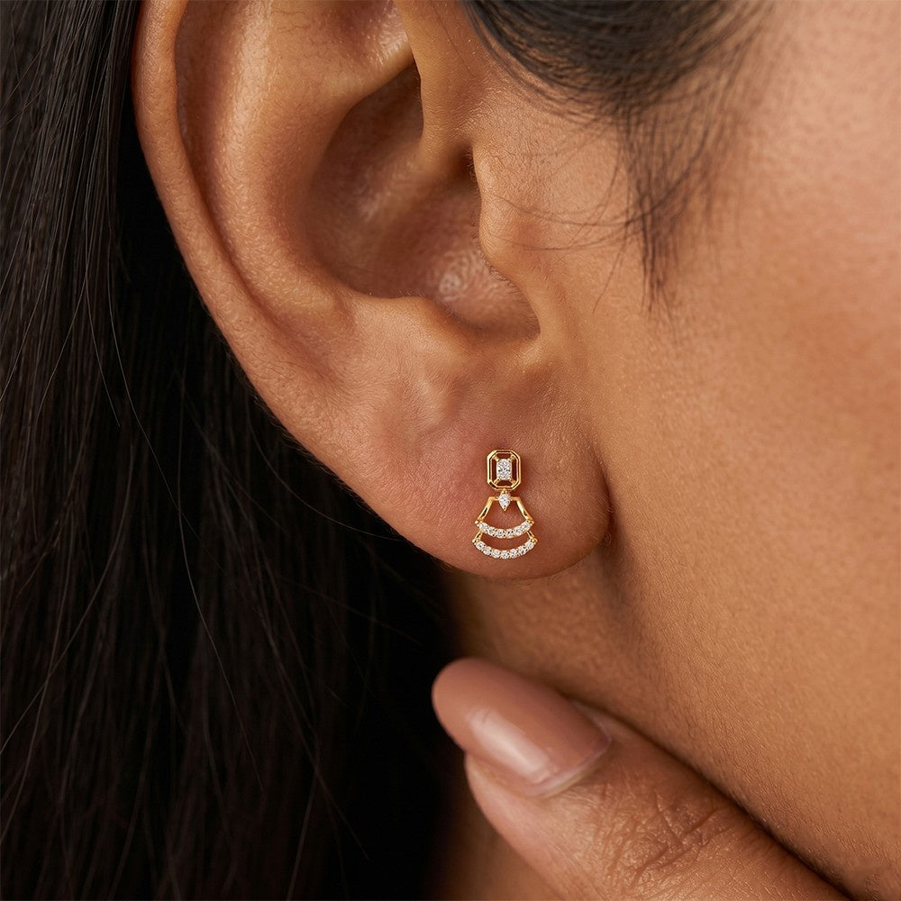 A close-up of a person's ear wearing a gold earrings with diamond accents, featuring a geometric design.