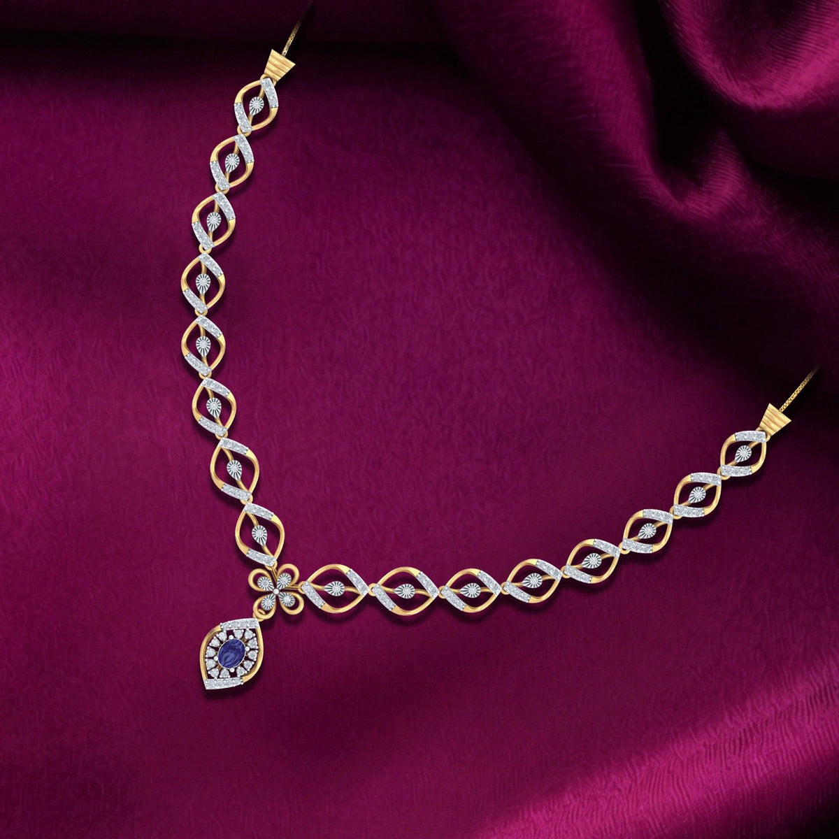 Gold and diamond necklace with a teardrop-shaped blue, displayed on a draped magenta satin fabric.