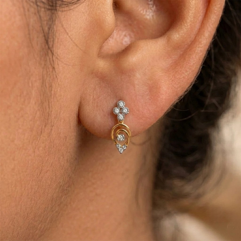 A close-up of a person's ear wearing a Gold and diamond drop earrings with floral designs.