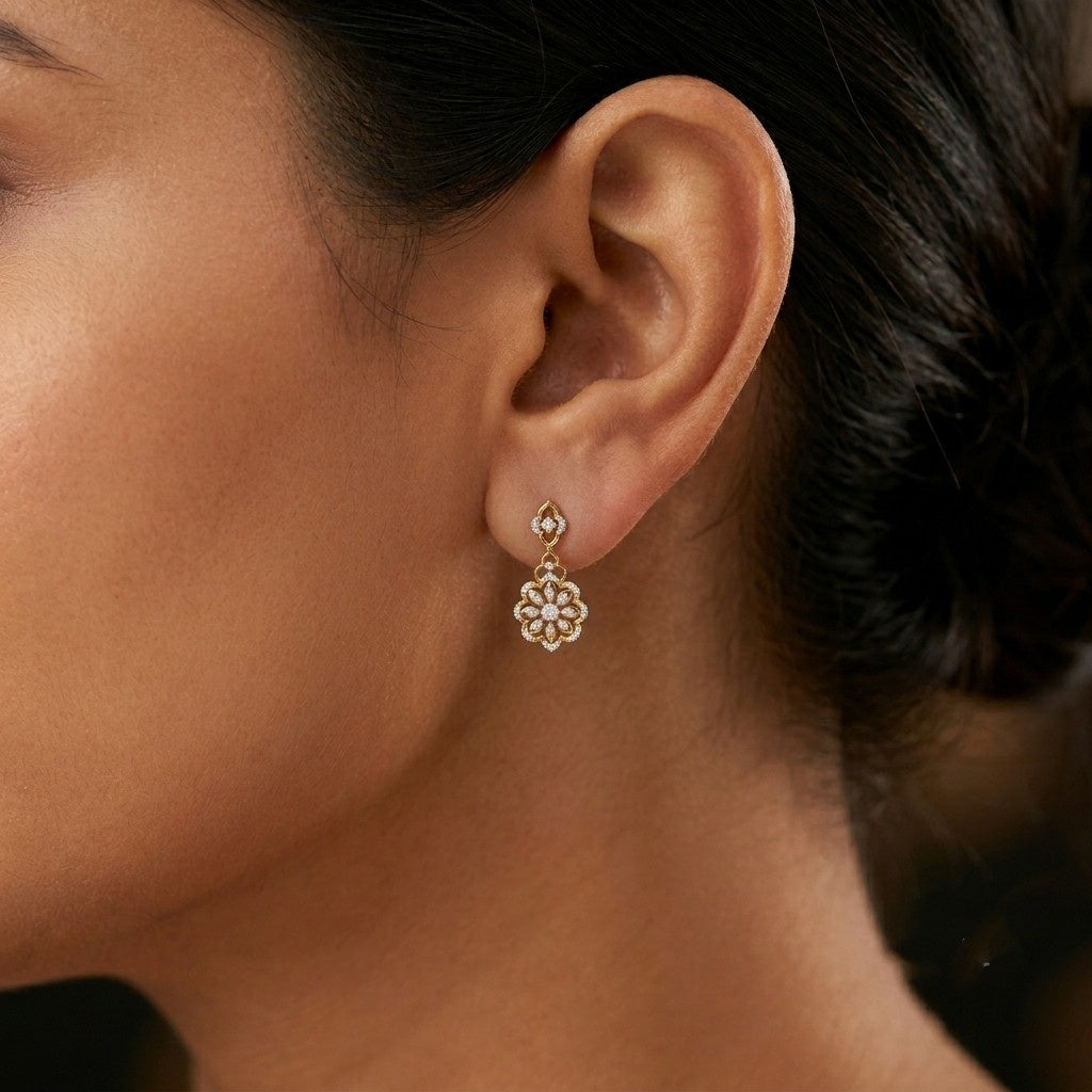 A close-up of a woman's ear wearing a delicate gold dangle earring.