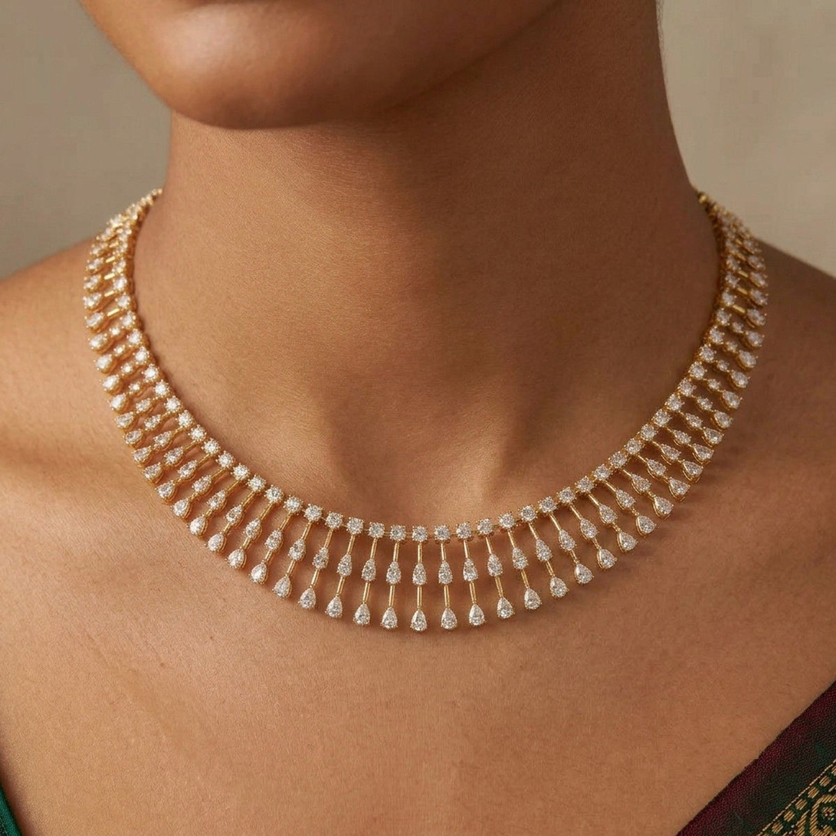 A close-up of a model wearing a gold and diamond necklace with dangling teardrop-shaped.